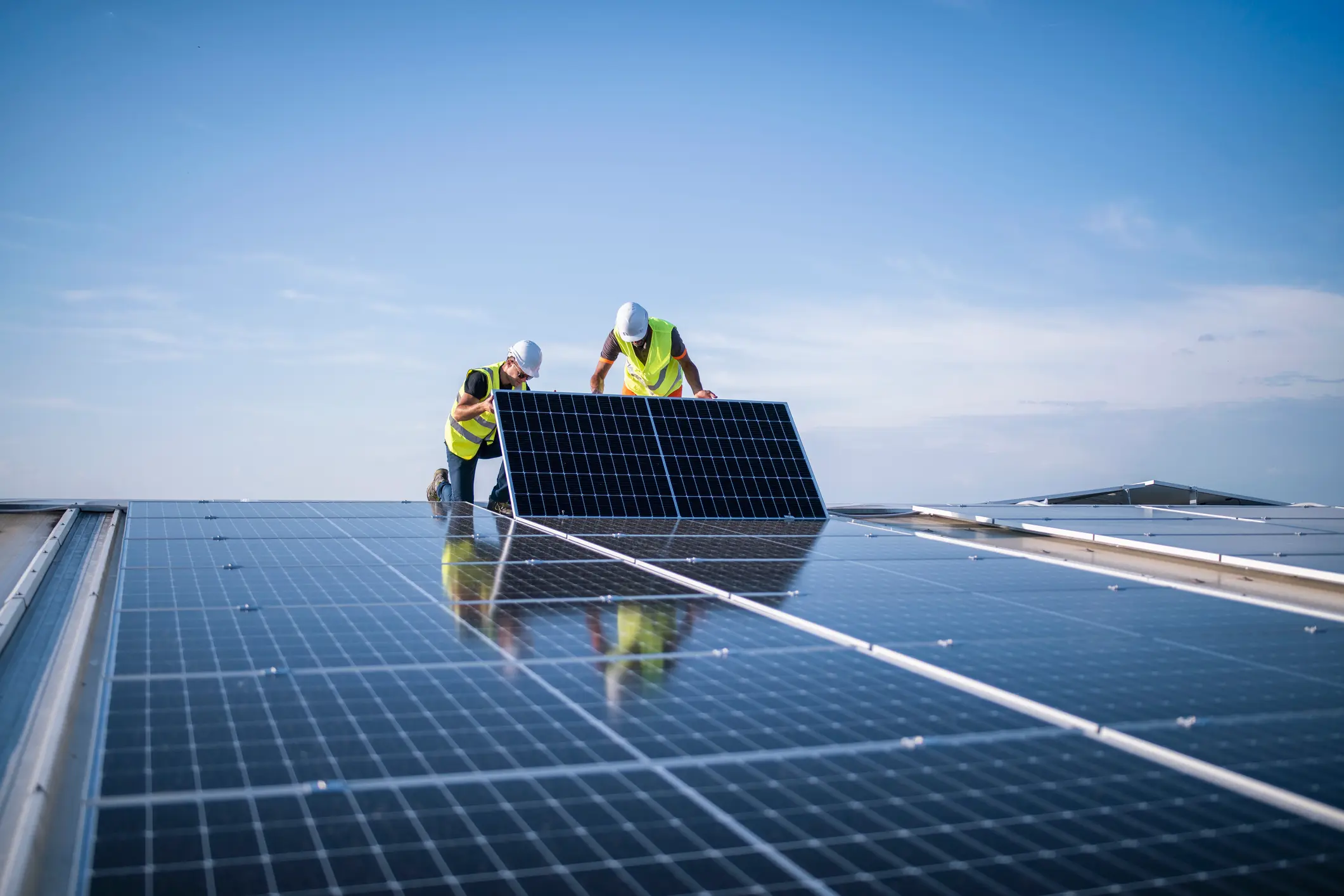 Zwei Arbeiter montieren Photovoltaikmodule auf einem Dach